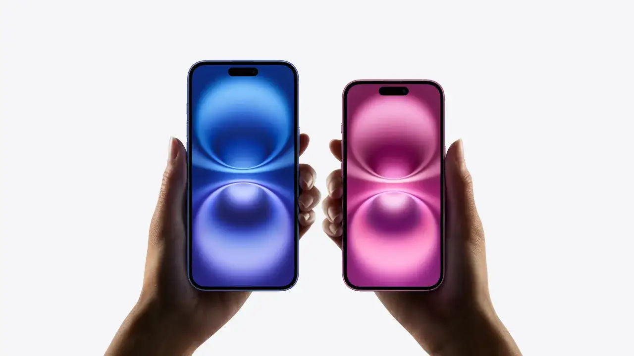Dwie dłonie trzymają nowe iPhone'y: niebieski i różowy. Czekamy na premierę iPhone 16.